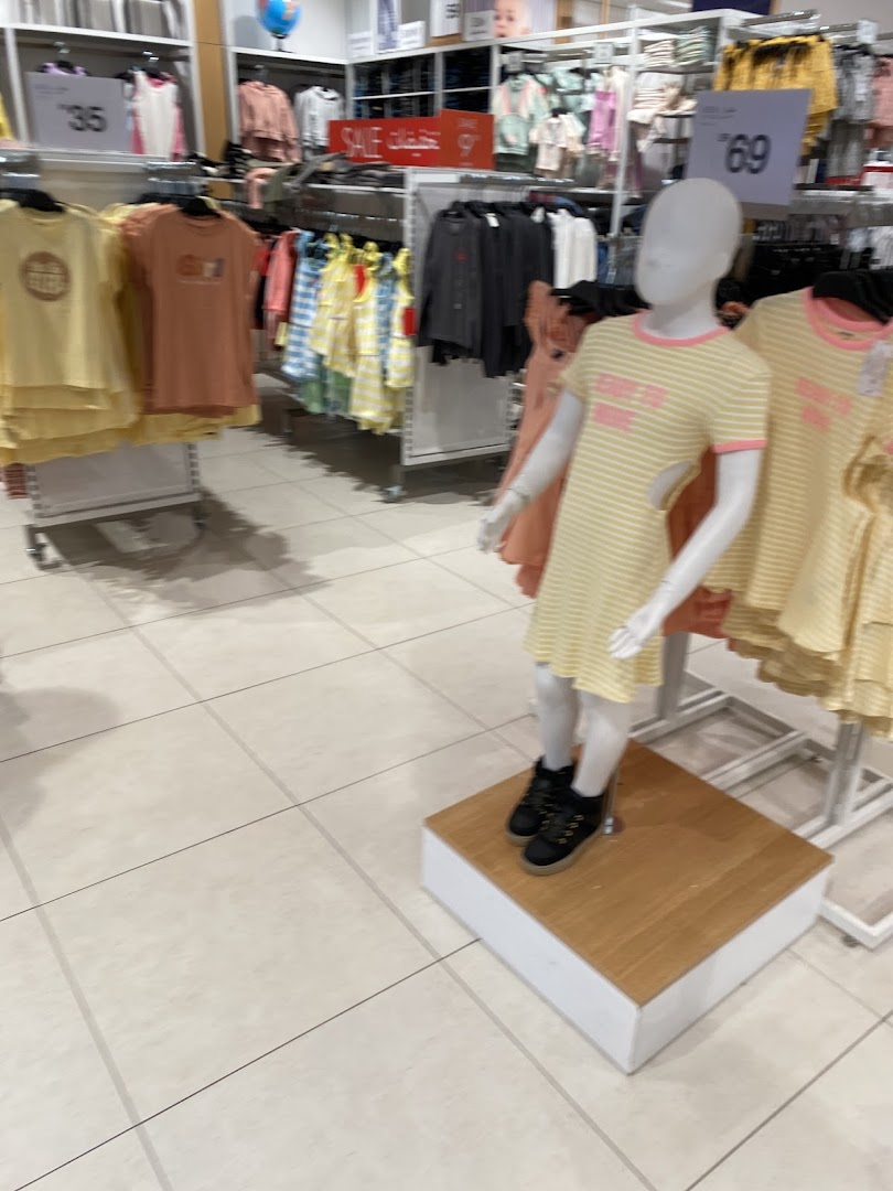 A brightly lit children's clothing store with mannequins displaying colorful outfits.