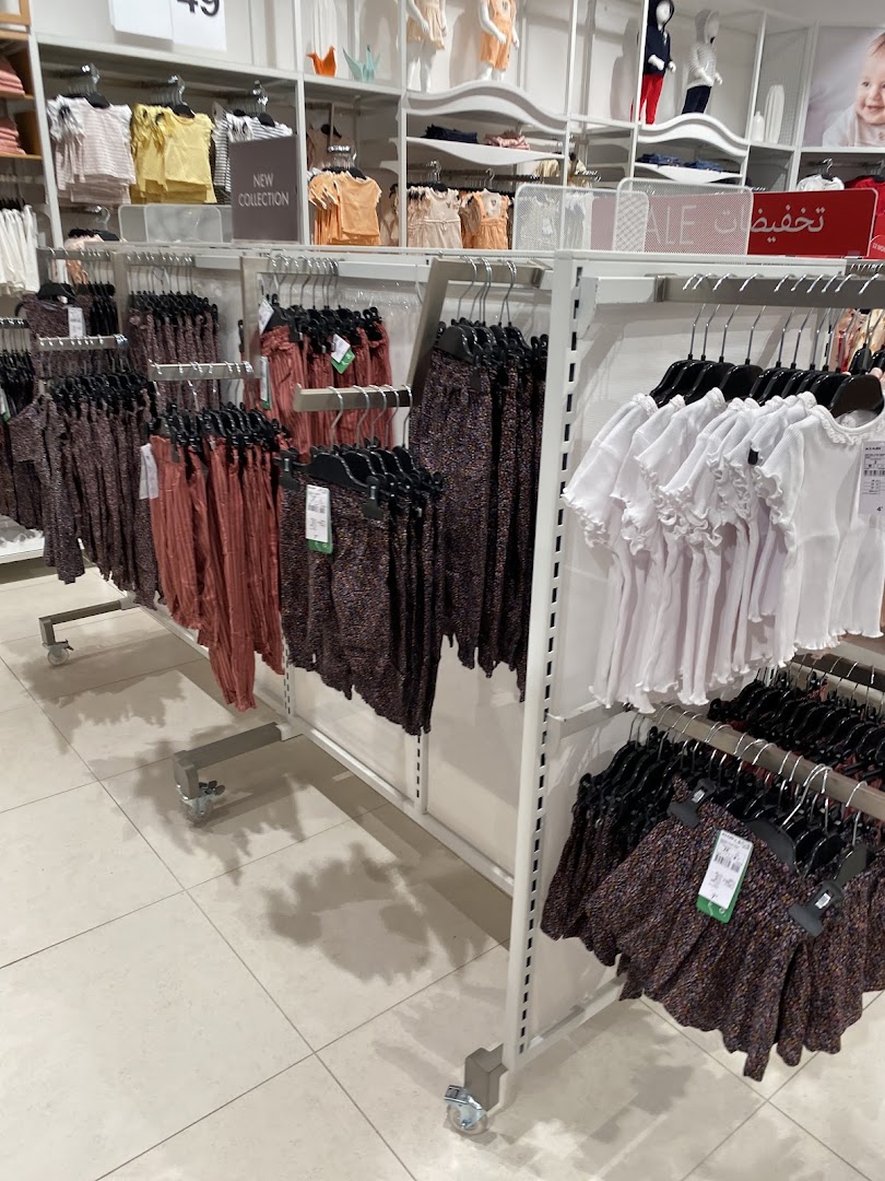 Interior view of a children's clothing store with racks of colorful apparel and mannequins.