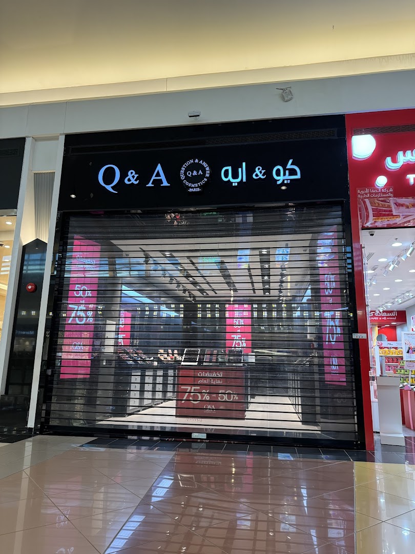 The storefront of Q&A Cosmetics, with the shutters down, displaying sale signs.