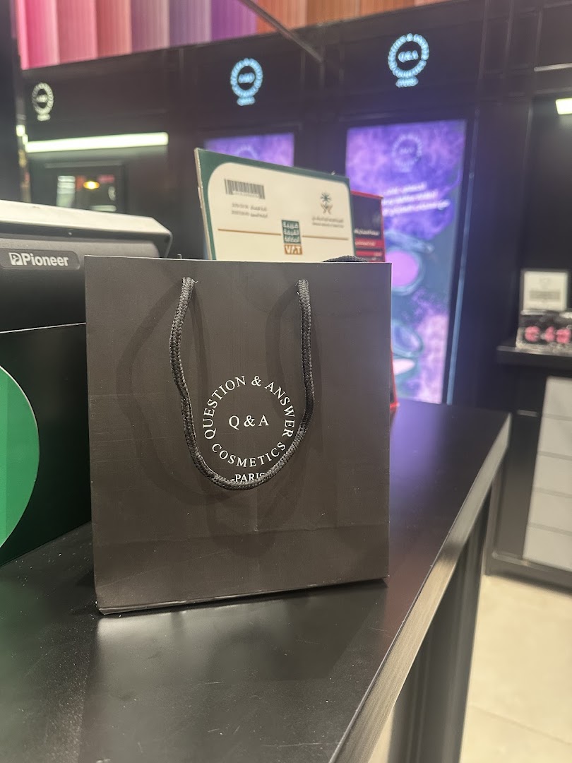 A black shopping bag with the Q&A Cosmetics Paris logo sits on a counter.
