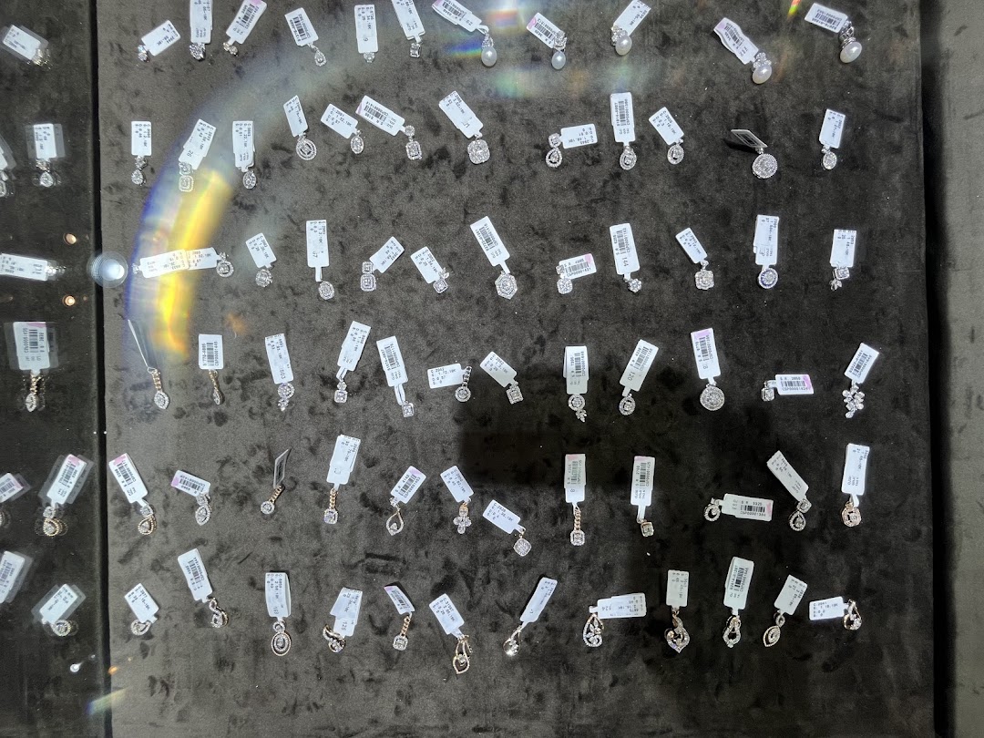 A display of various diamond pendants and earrings with price tags.