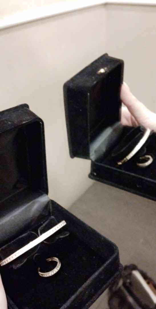 Two black velvet jewelry boxes are open, displaying sparkling bracelets and rings.