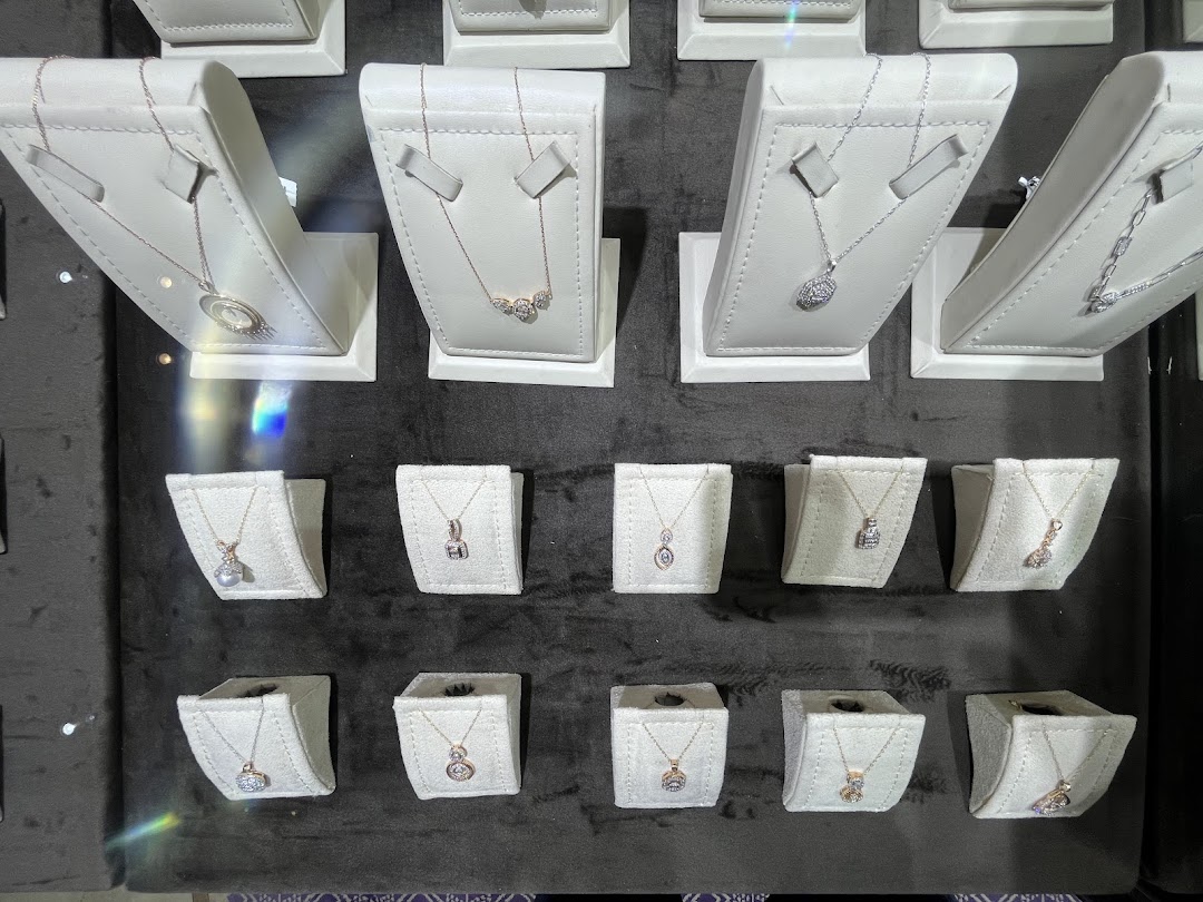 A display of various delicate necklaces with pendants on white stands.