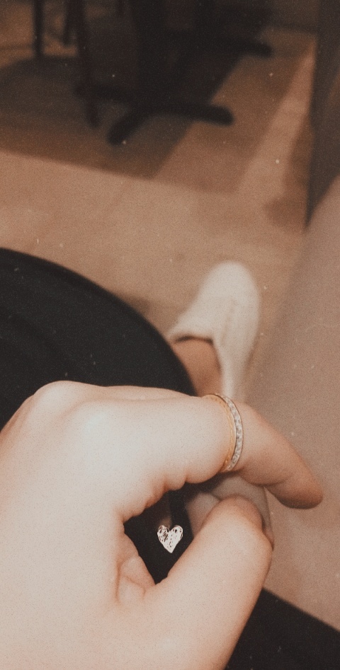 Close-up of a hand wearing rings, with a small heart detail.