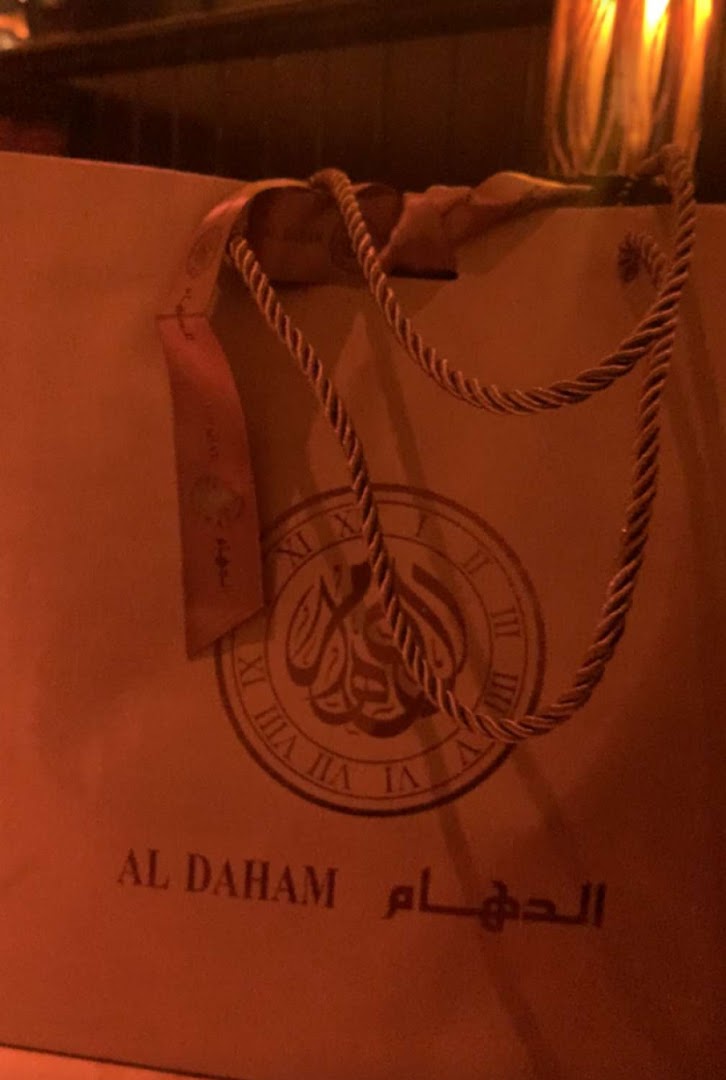 A shopping bag with the ALDAHAM logo and Arabic script, featuring rope handles.