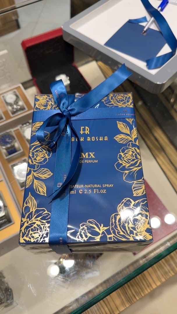 A beautifully packaged perfume box with a blue ribbon and gold floral design.