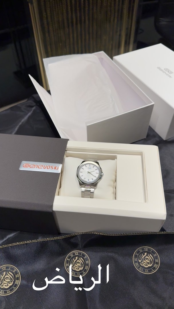 A silver Genevoski watch is displayed in its open packaging with Arabic text in the foreground.