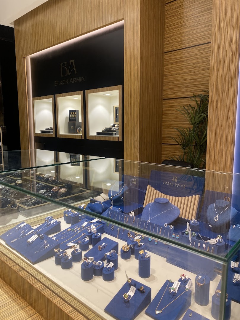 A jewelry store display featuring necklaces, rings, and watches in a modern, well-lit setting.