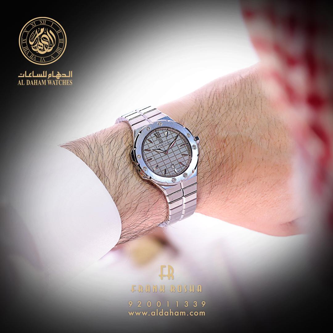 A close-up shot of a man's wrist wearing a stylish silver watch with a patterned dial.