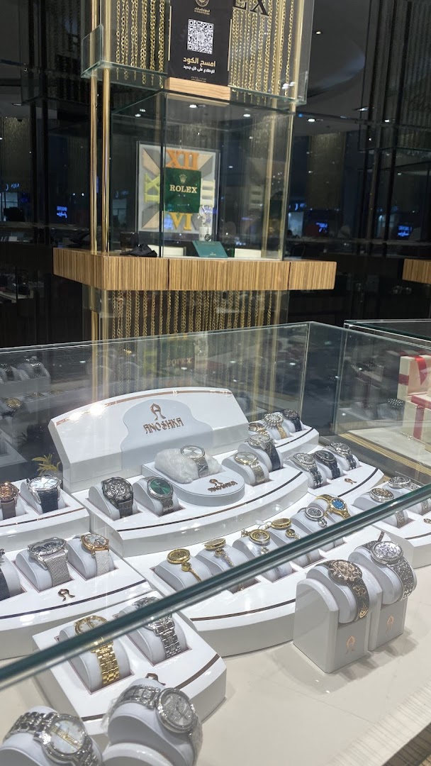 A display case filled with various luxury watches, featuring brands like Rolex and Anoshka.