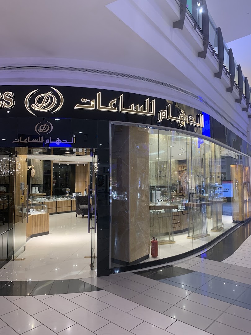 The exterior of a luxury watch shop, ALDAHAM, with illuminated signage and a well-lit interior.