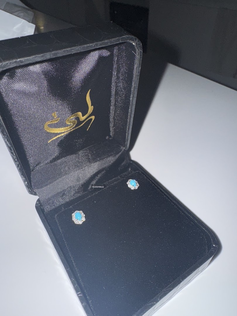 A pair of turquoise and diamond stud earrings in a black velvet jewelry box.