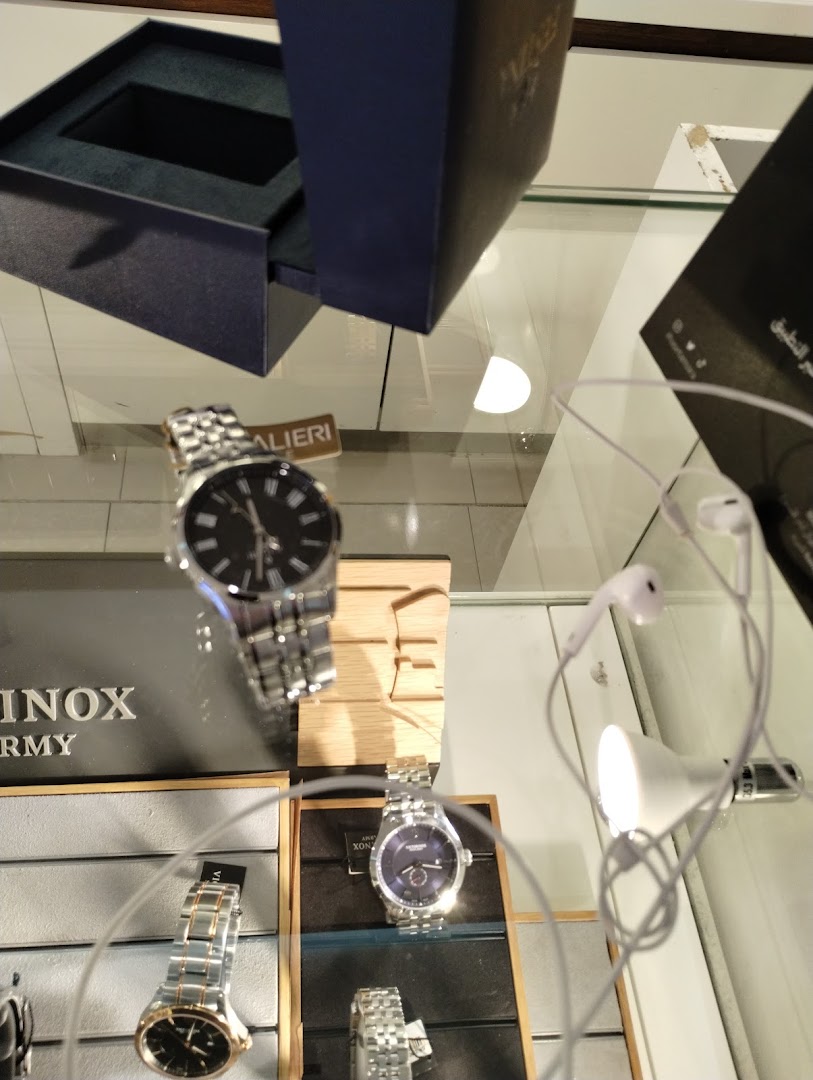 A display case showcasing various luxury watches and a pair of white earphones.