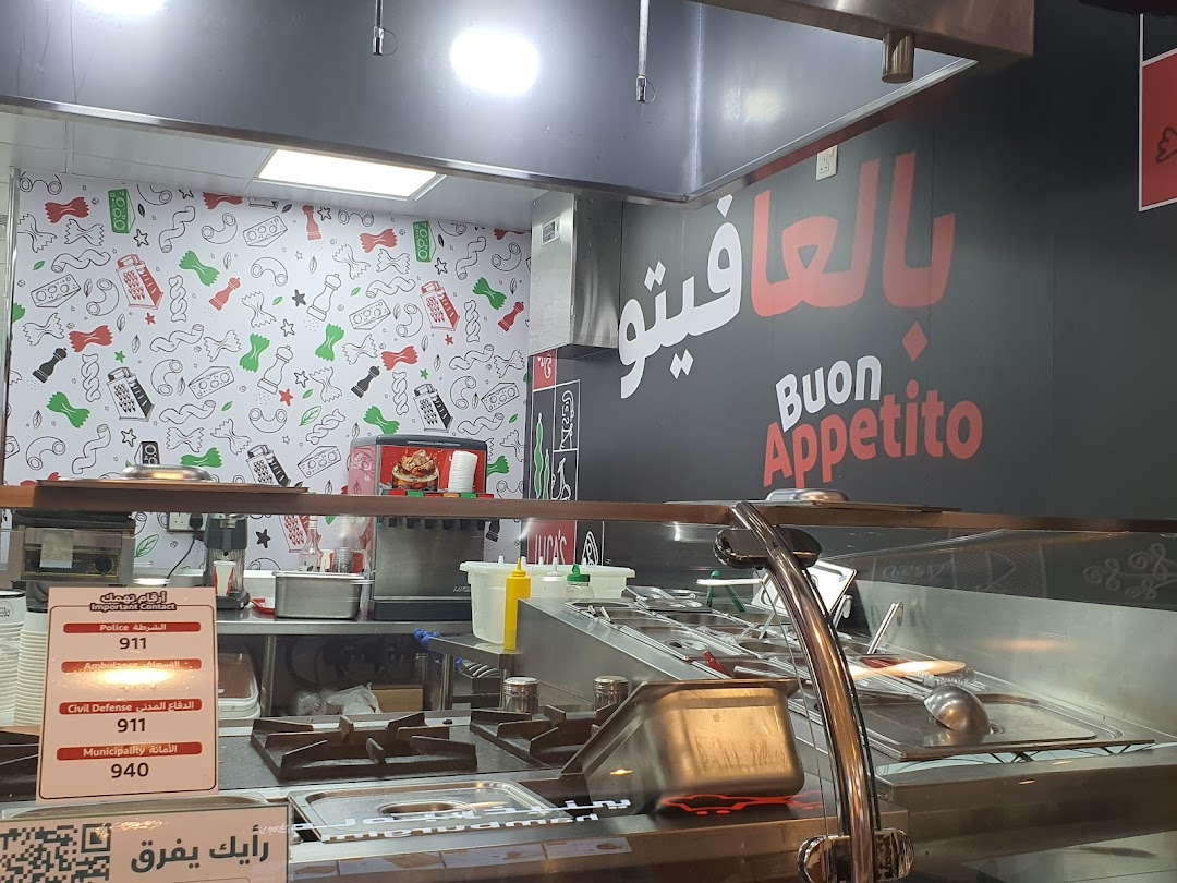 Interior view of a food establishment with kitchen equipment and decorative wall.