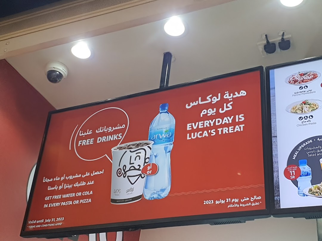 A digital menu board advertising free drinks with pasta or pizza purchases.