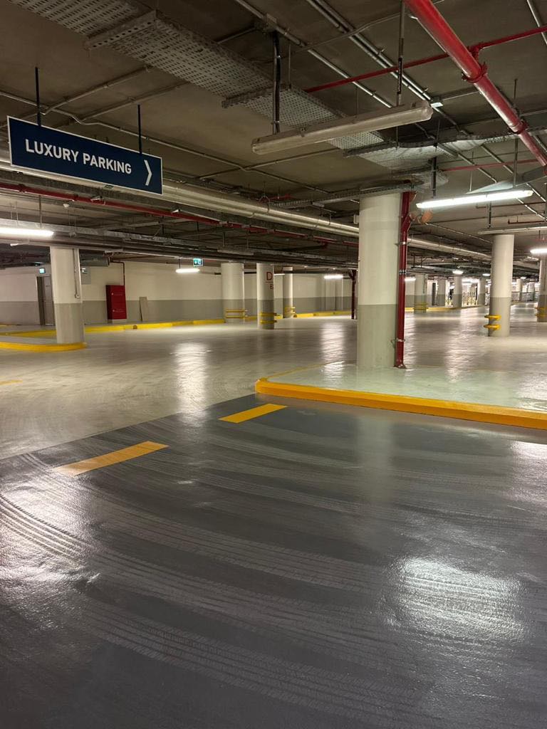An empty, well-lit underground parking garage with a sign indicating 'Luxury Parking'.