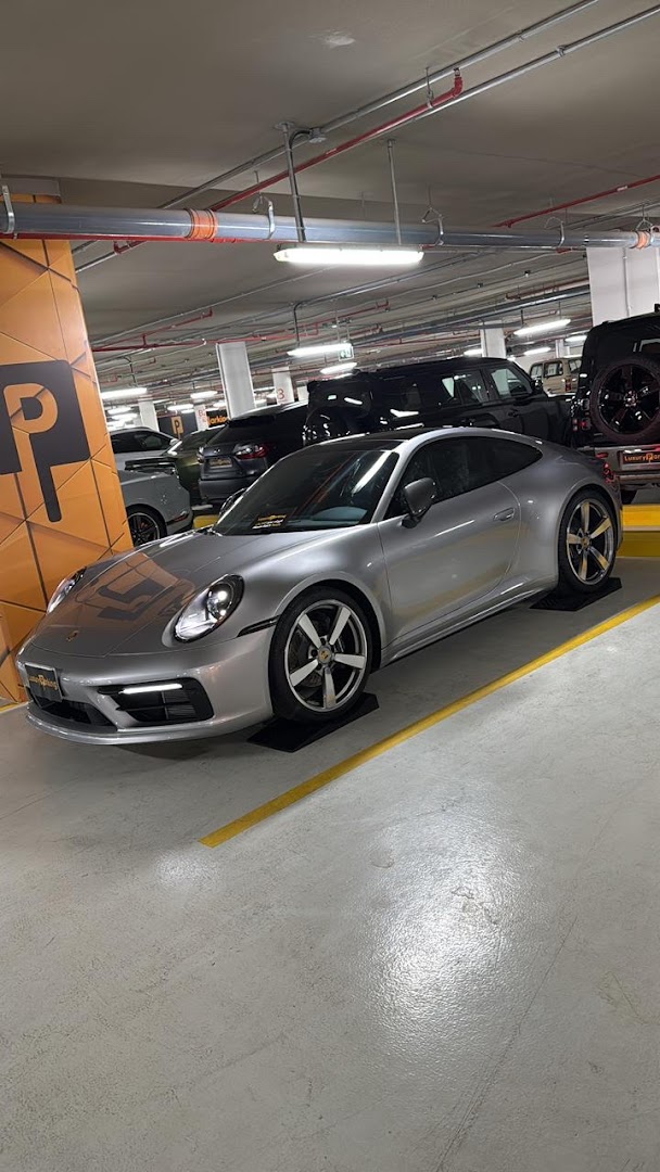 A silver Porsche 911 parked in a well-lit indoor parking garage.