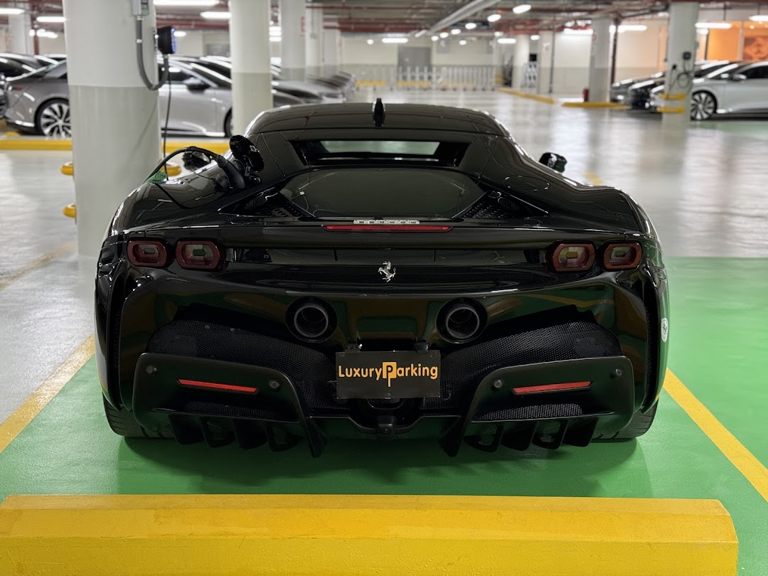 A black luxury sports car parked in a well-lit parking garage with charging stations.