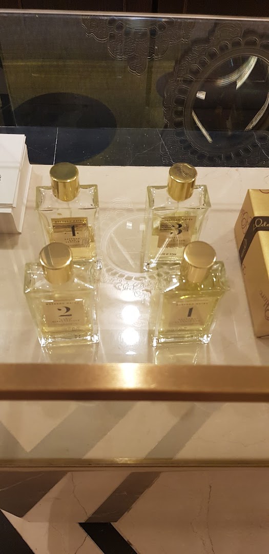 A display of four numbered perfume bottles with gold caps on a reflective surface.