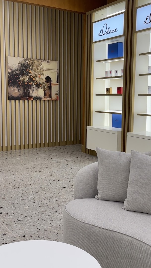 Interior of a modern luxury boutique with shelves displaying perfume bottles and boxes.