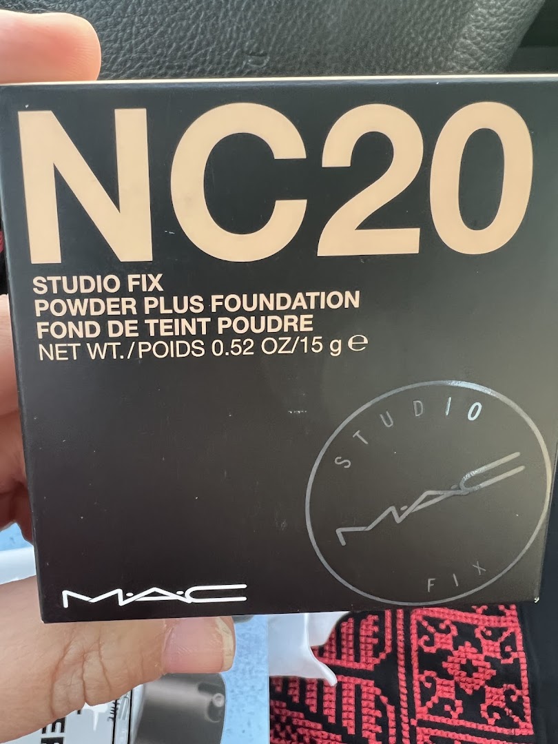 A hand holds a box of MAC Studio Fix Powder Plus Foundation in shade NC20.