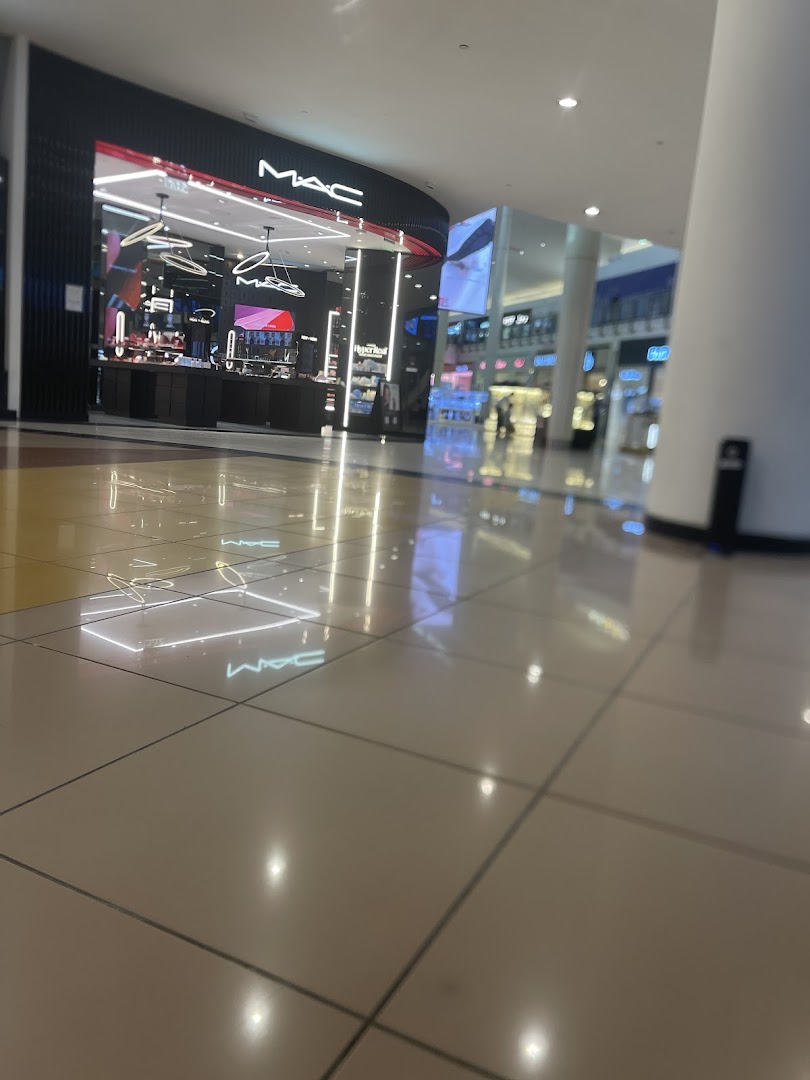 The exterior of a MAC cosmetics store in a brightly lit shopping mall.