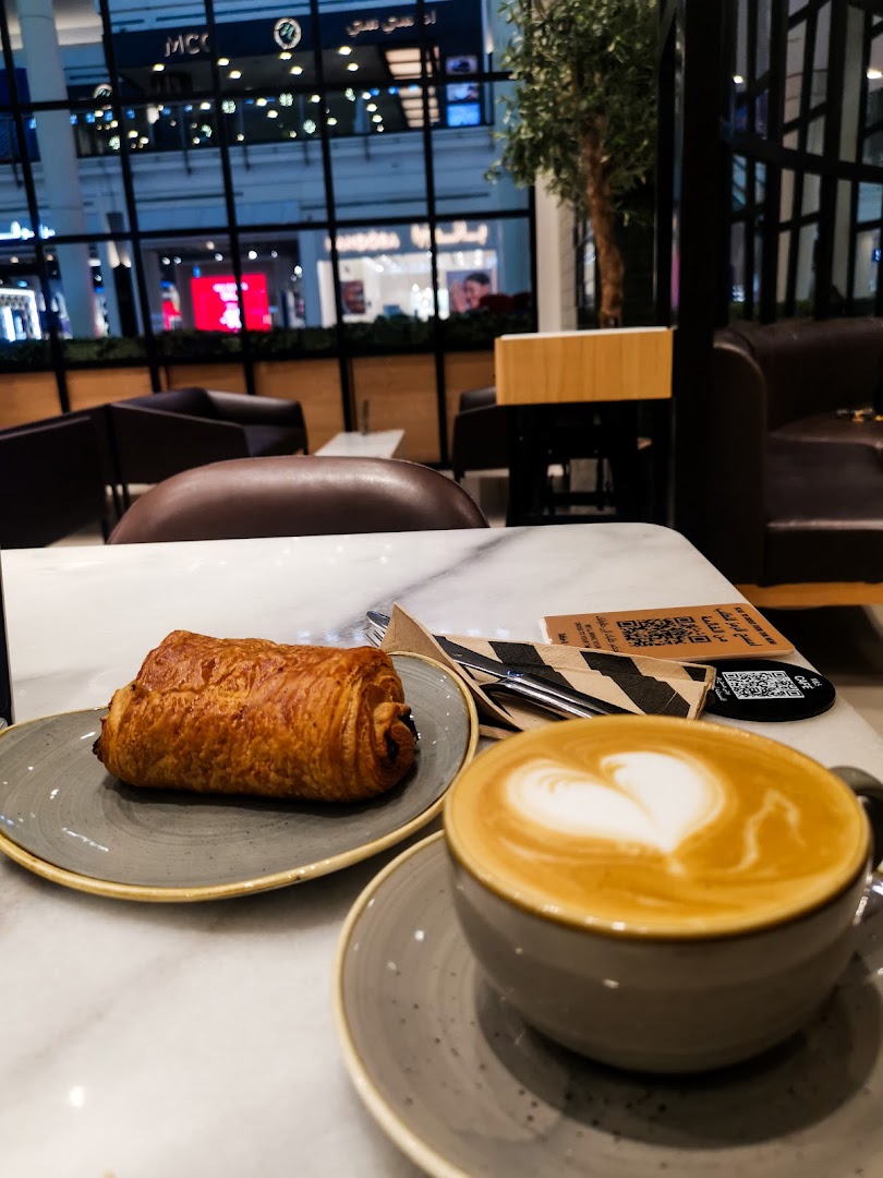 A delicious pastry and a latte with heart art on a marble table at MS FOOD and MS CAFE.