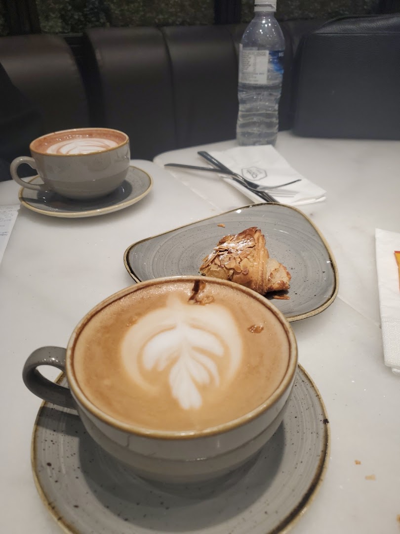 Two cups of coffee with latte art and a pastry on a table.