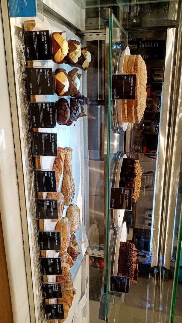 A display case filled with various pastries, muffins, and cakes from MS FOOD and MS CAFE.