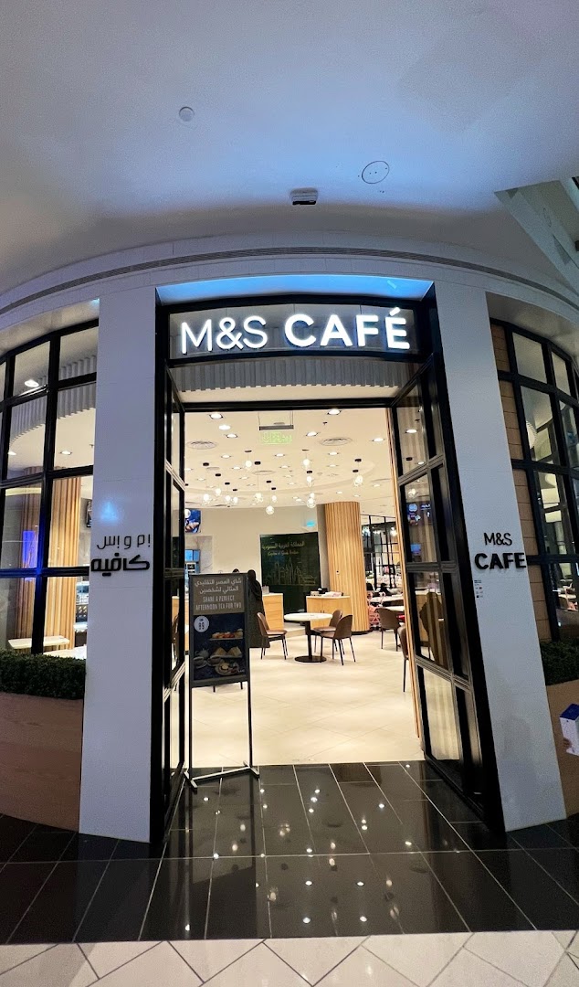The entrance to M&S Cafe, with seating visible inside and a promotional sign.