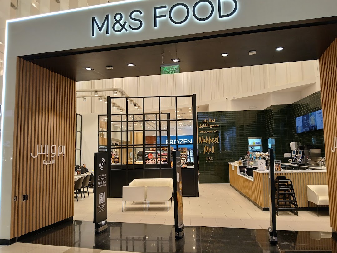 The entrance to M&S Food and M&S Cafe, featuring a modern design with wooden accents and a cafe counter.