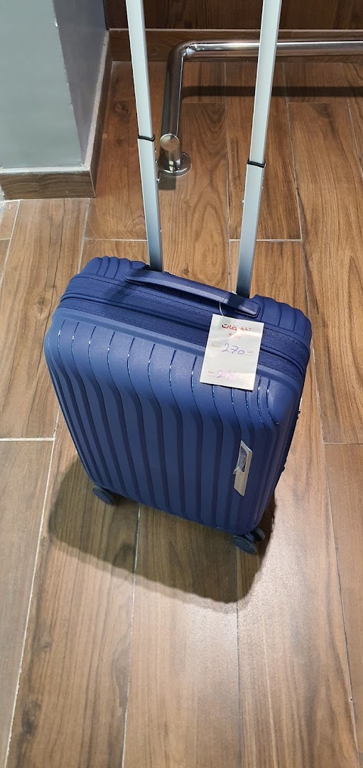 A blue suitcase with a price tag is displayed on a wooden floor.