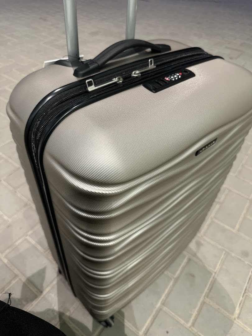 A close-up shot of a silver hardshell suitcase with a TSA lock.