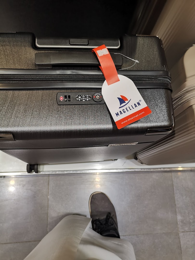 A close-up of a Magellan suitcase with a red tag showing price and website.