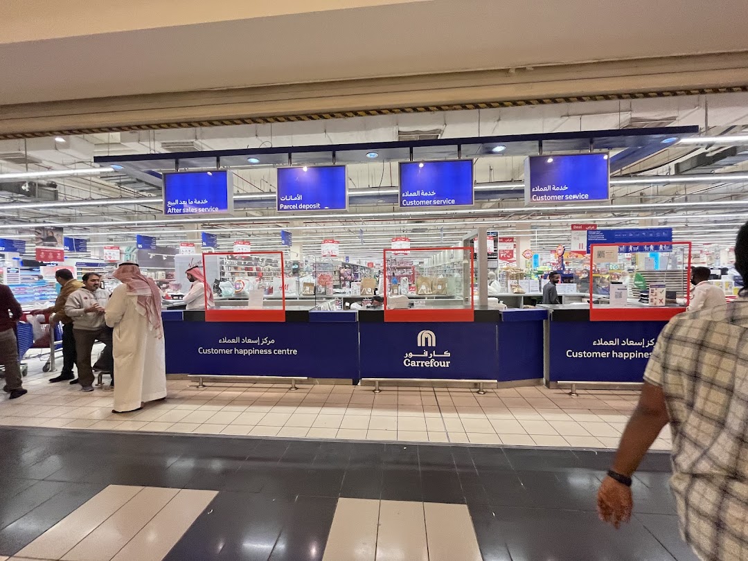A customer service counter at a Carrefour hypermarket with various service signs.
