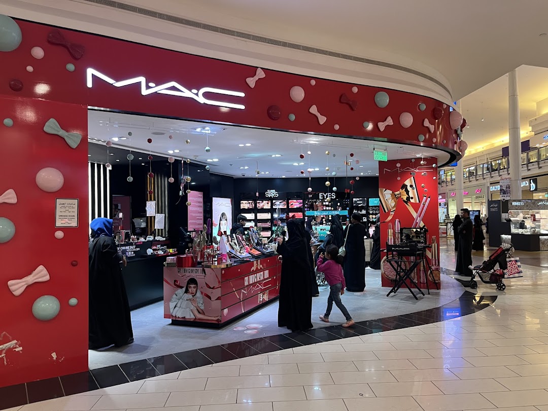 The MAC cosmetics store front in a mall, decorated with festive bows and spheres.