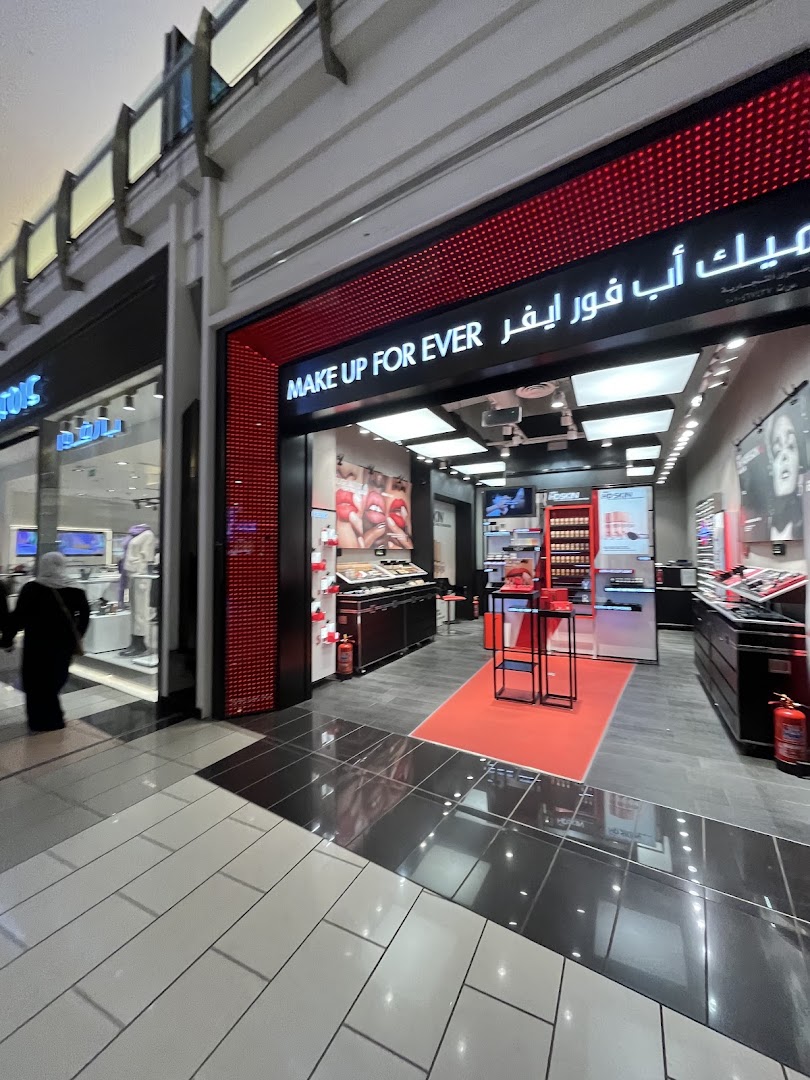 The entrance of a MAKE UP FOR EVER cosmetics store with displays of makeup products.