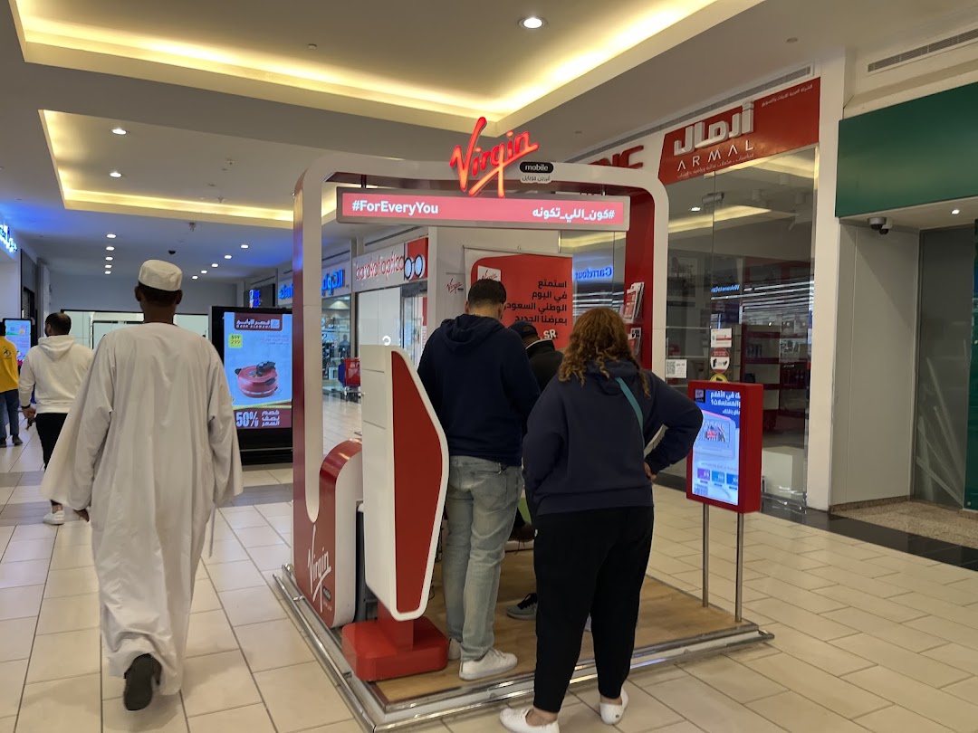 People interacting with a Virgin Mobile kiosk in a shopping mall.