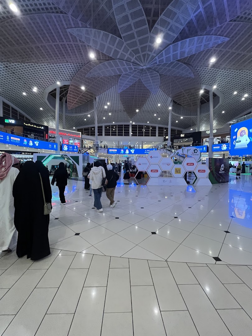 A wide view of a modern shopping mall interior with people walking and various displays.