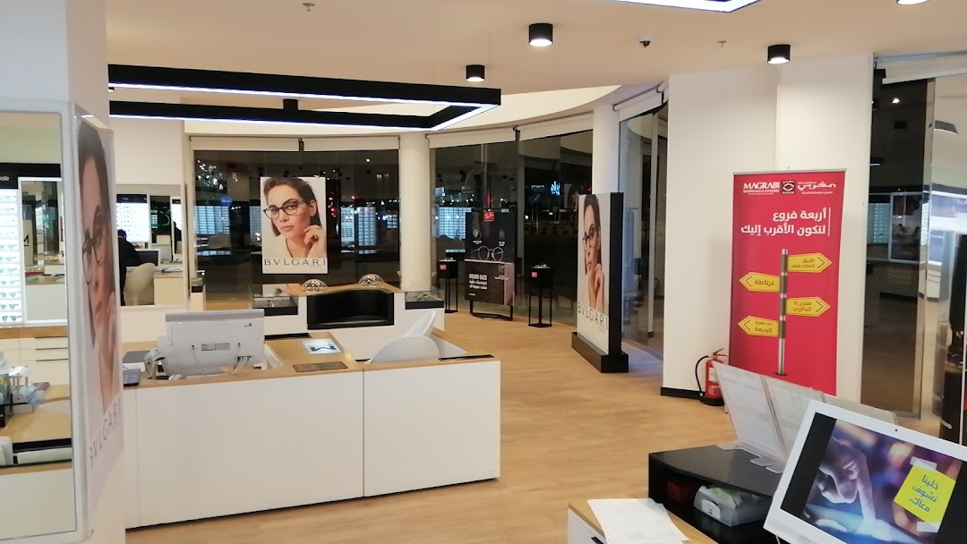 Interior view of a modern optical shop with displays of glasses and promotional banners.