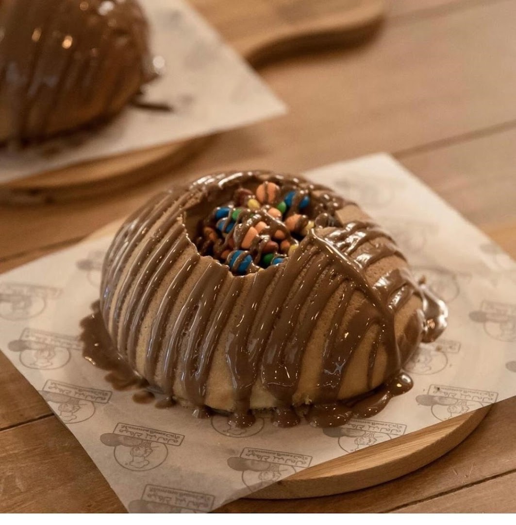 A delicious dessert bun filled with candies and drizzled with chocolate sauce.