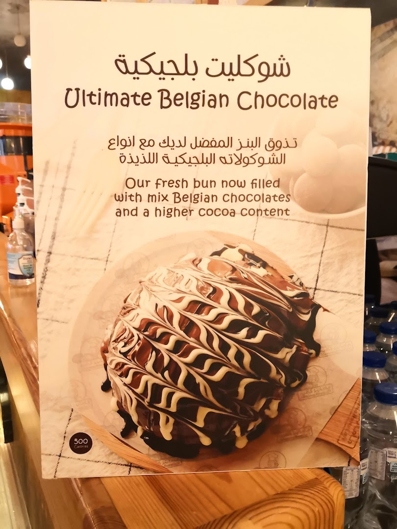 A sign advertising an Ultimate Belgian Chocolate bun with a picture of the bun.