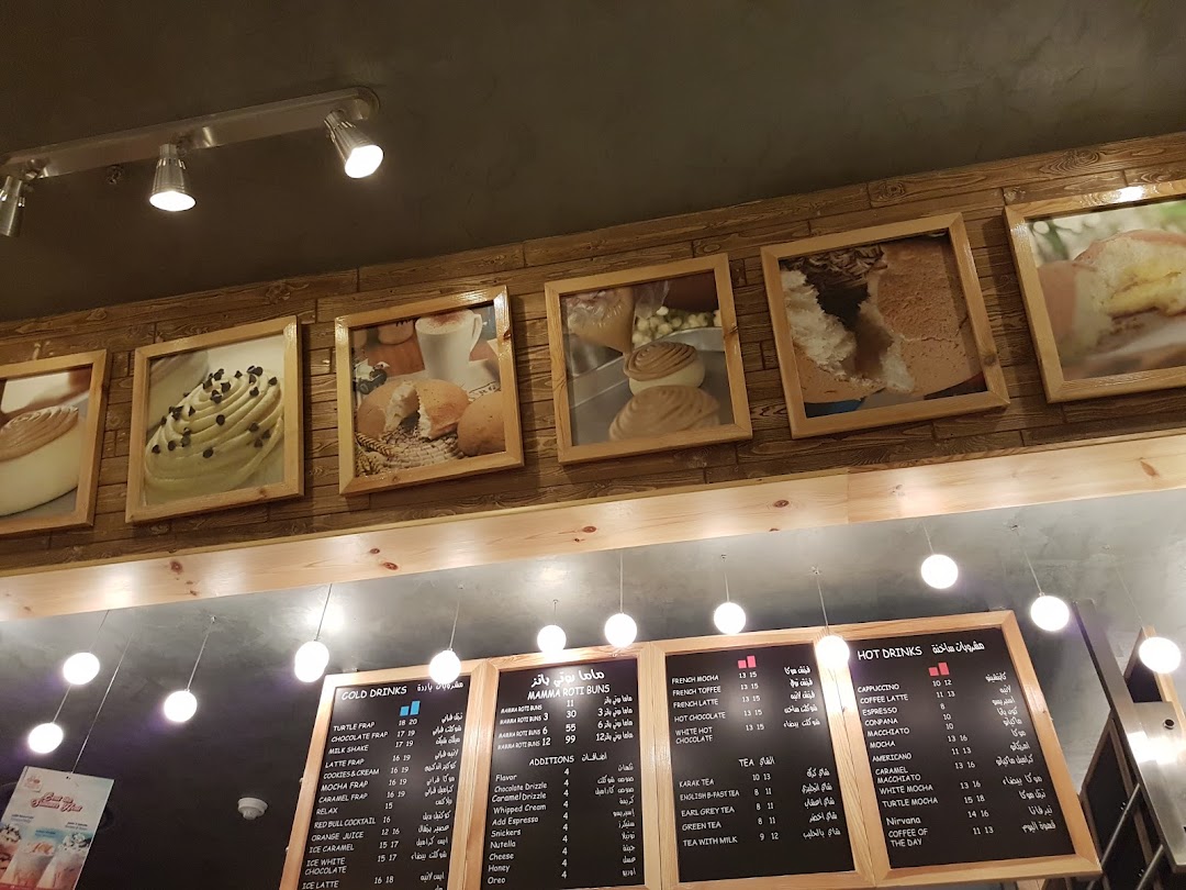 A wall with framed pictures of pastries and a menu board with drinks and additions.