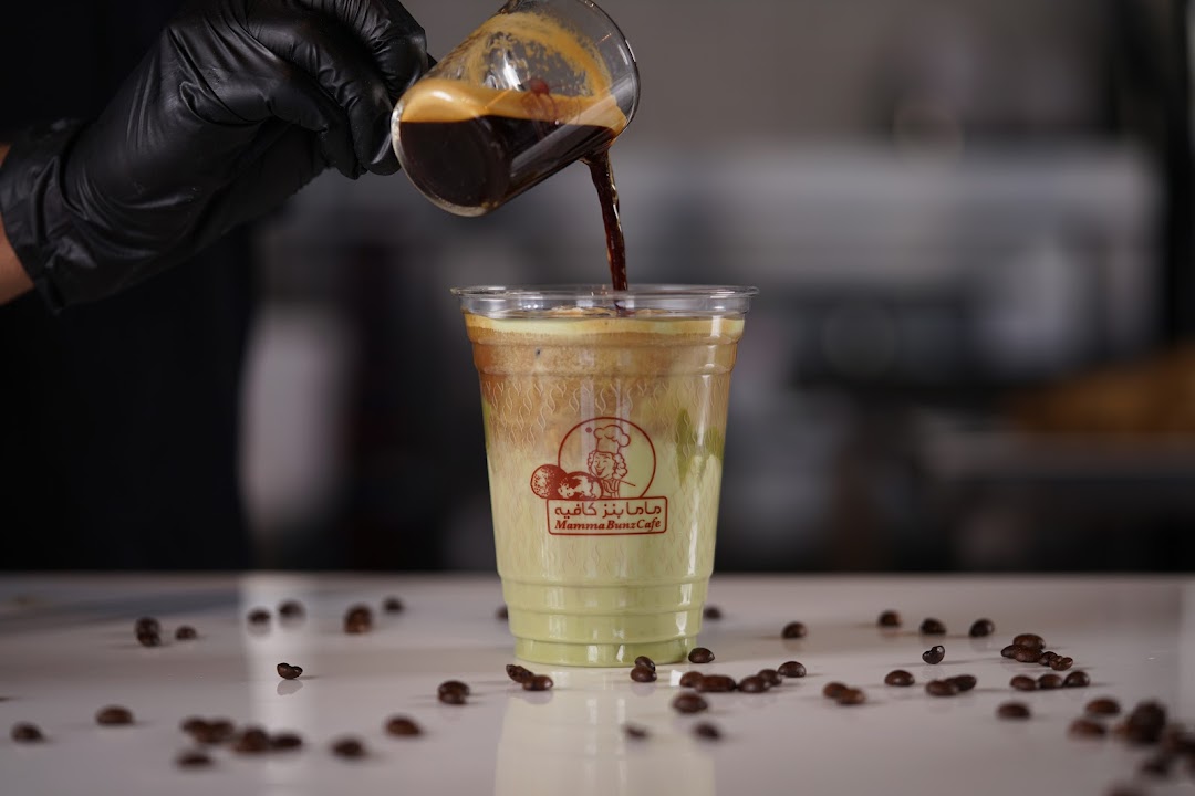A barista pours espresso into a layered iced coffee drink at MammaBunz Cafe.