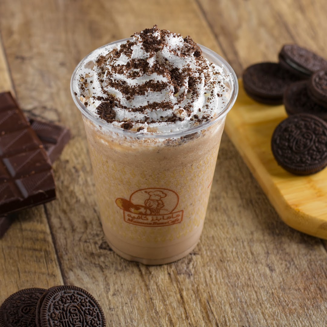 A delicious chocolate milkshake topped with whipped cream and cookie crumbles, with chocolate and cookies on the side.