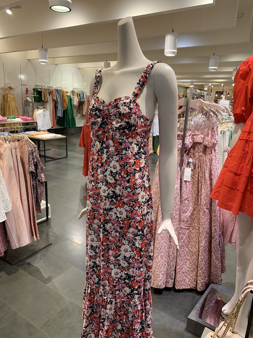 Mannequin wearing a floral maxi dress in a clothing store.