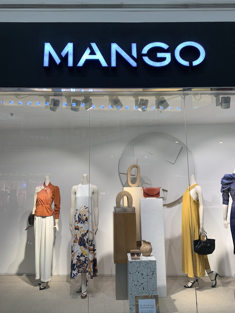 Mango store window display featuring mannequins dressed in stylish outfits and accessories.