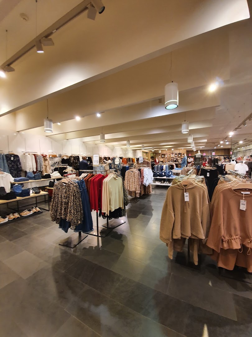 Interior view of a well-lit clothing store with racks of apparel and displays.