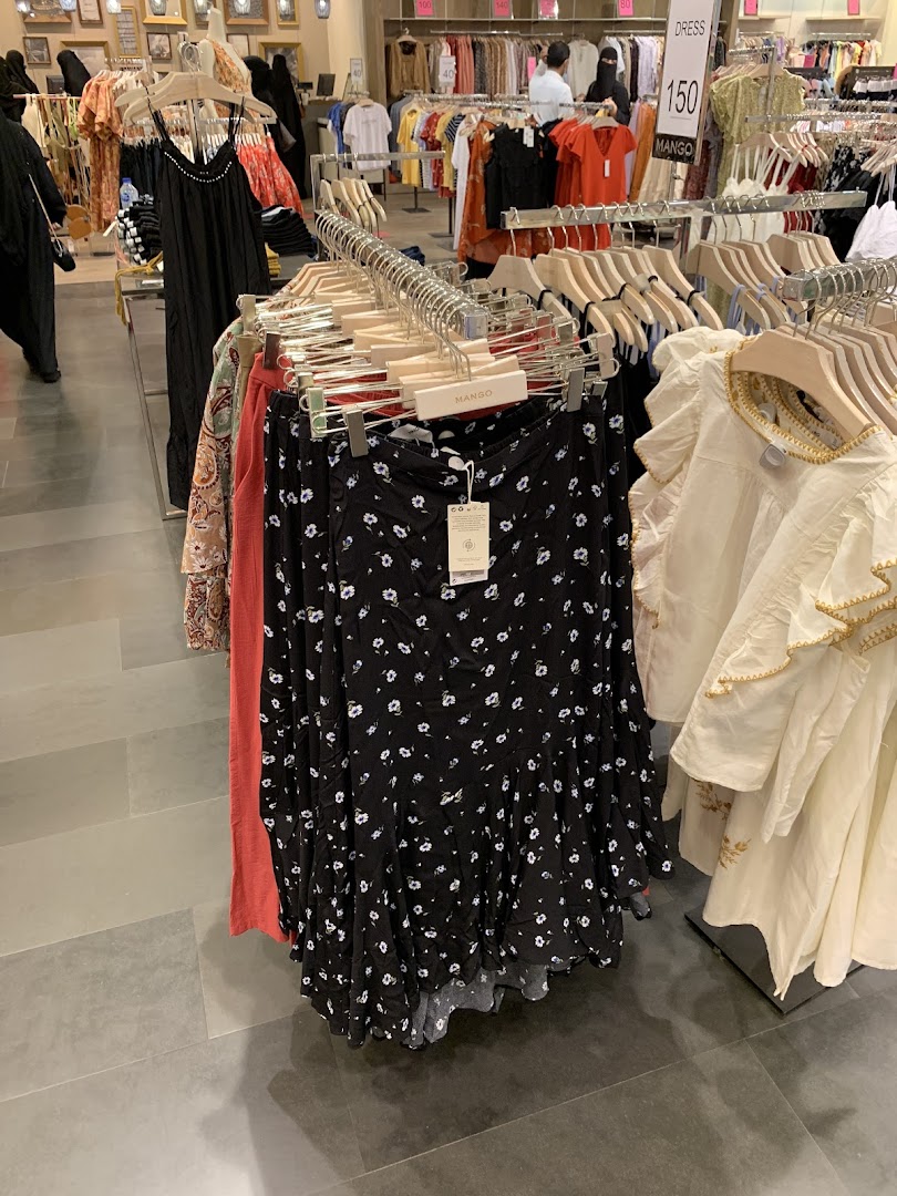 A clothing store interior with racks of dresses and skirts, featuring a floral print skirt in the foreground.