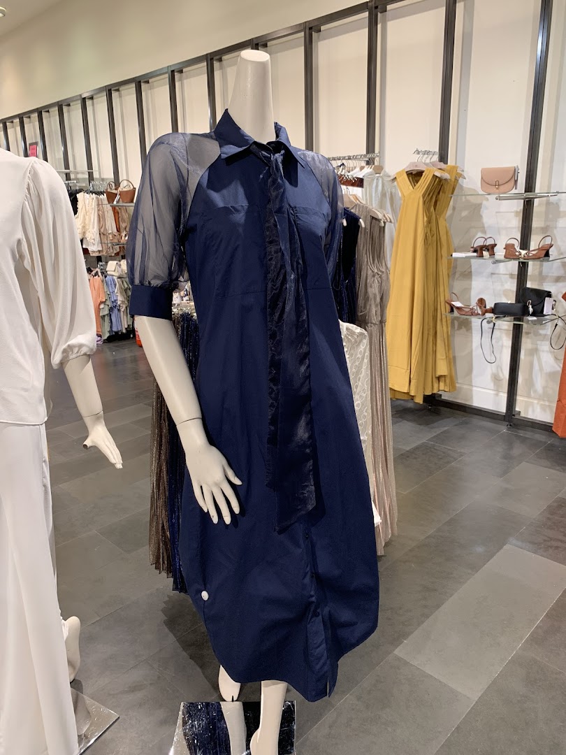 Mannequins display stylish dresses and accessories in a well-lit retail store.